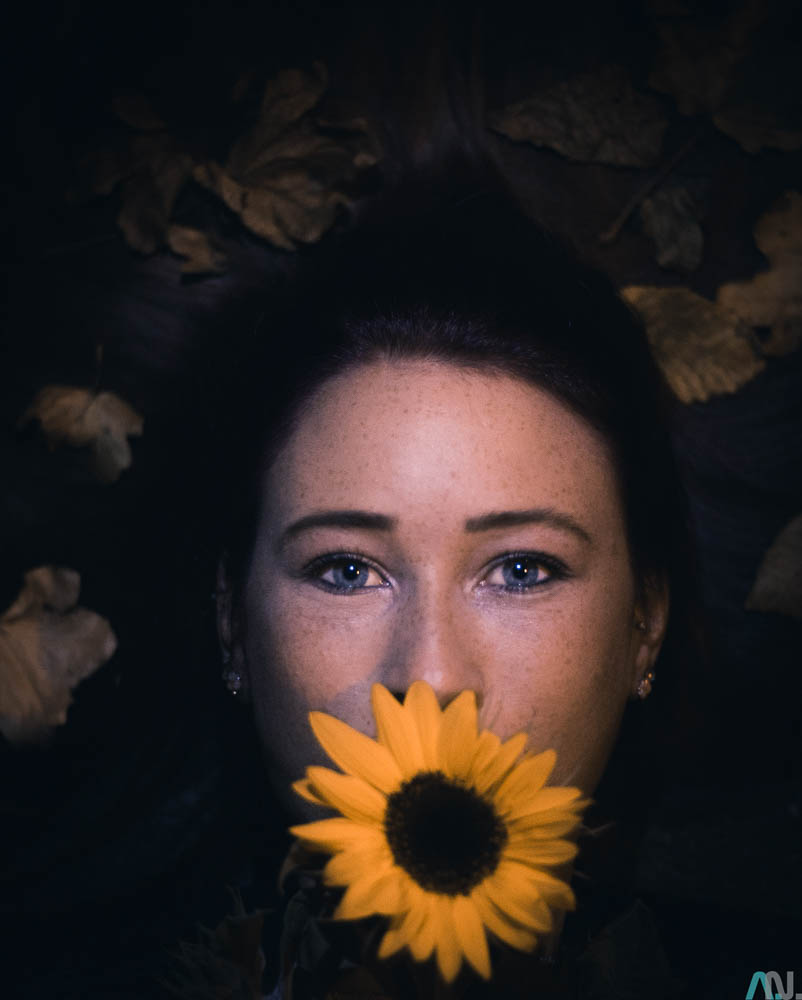Frau mit Sonnenblume in dem Mund